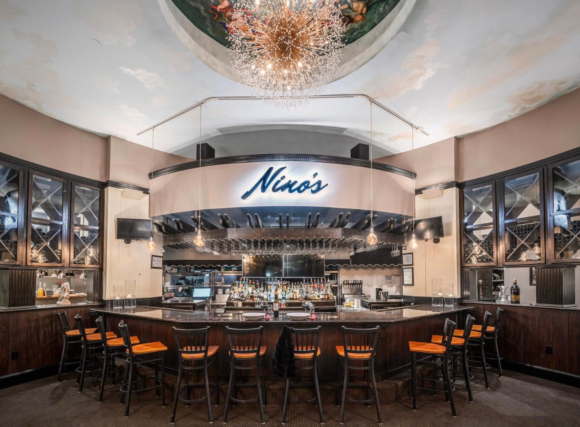 The bar beneath the painted ceiling and chandelier