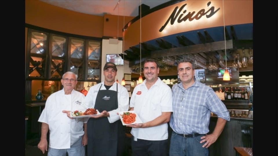 Nino's team holding plates at the bar